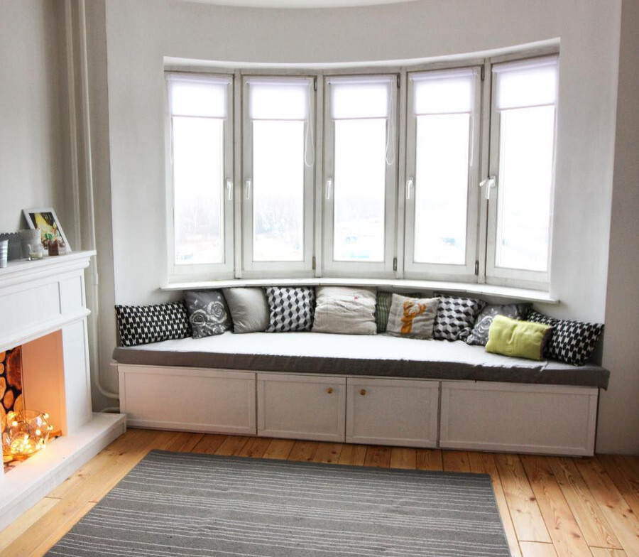 Идея для дизайна гостиной с эркером: диван-подоконник с системой хранения