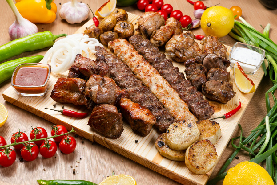 Мясо и кебабы на доске с овощами