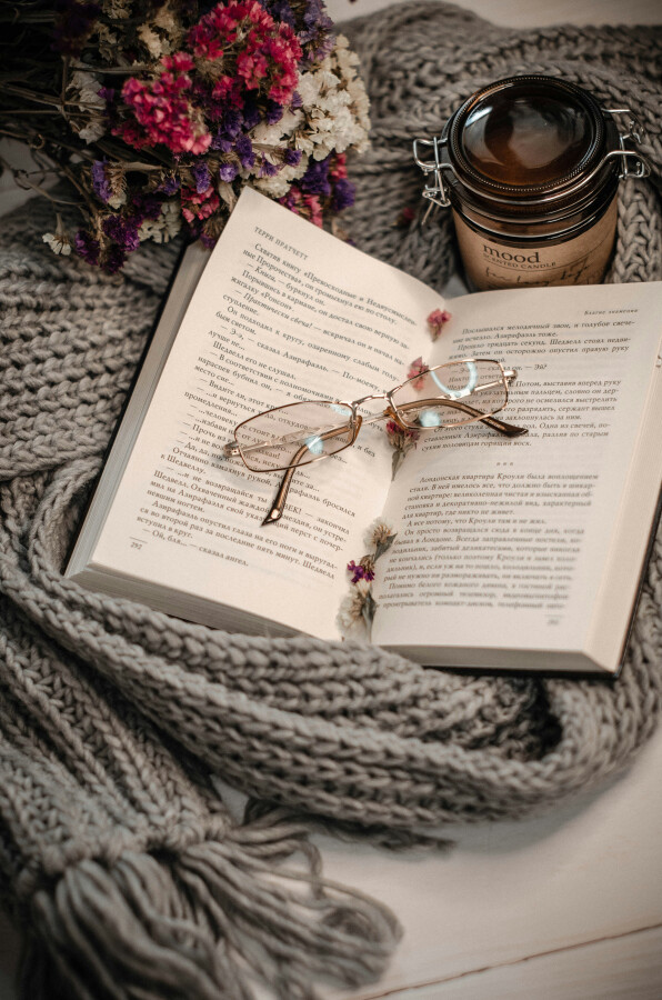 Открытая книга, свеча и мягкий шарф 
